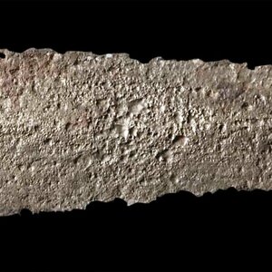 Гладиус, сохранивший скелет рукояти, с железной пластиной на гарде, полукуполом в верхней части навершия и тремя небольшими промежуточными дисками; Общая длина 58,3 см (лезвие 42,8 см, минимальная-максимальная ширина клинка 42-66 мм, вес 407 г). Датируется концом I века до н. э. и серединой I века н. э.