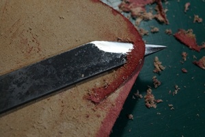 Trimming and working the leather edge before further assembly.
