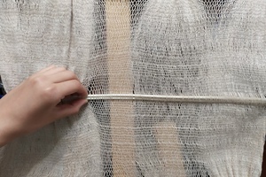 Working the sprang fabric on simple smooth sticks.