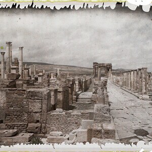 Тимгад / Thamugadi: Les ruines du forum, l'arc dit de Trajan et le Decumanus maximus - Timgad, Algérie; визуальный источник по памятнику, римский период, археологическая зона или музейный контекст.
